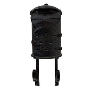 Puede incluir: Un buzón de pared de hierro fundido negro con una parte superior redondeada, una ranura horizontal para el correo y una puerta frontal con seis pequeños orificios de ventilación. La unidad incluye dos soportes decorativos en forma de voluta.