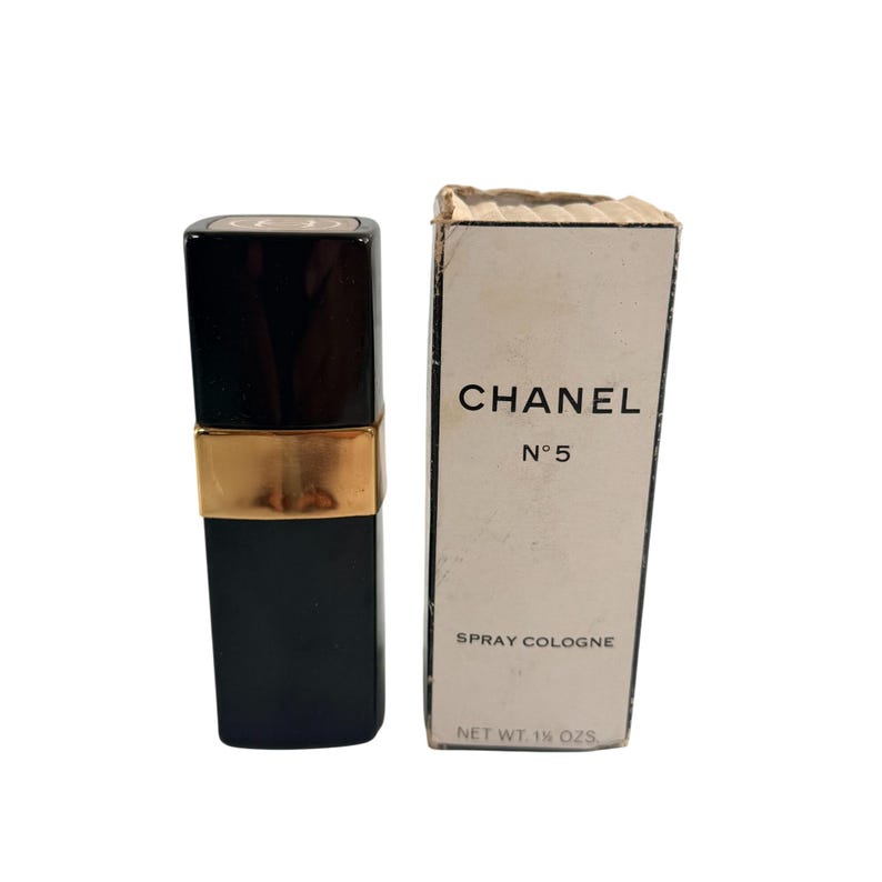 May include: A black Chanel No. 5 spray cologne bottle with a gold band and a matching box. The box is white with black text that reads "CHANEL N&deg;5 SPRAY COLOGNE NET WT. 42.5g."