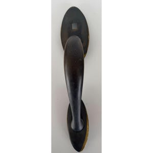 May include: A dark bronze-toned door handle featuring a curved grip and two oval-shaped mounting plates. The top plate includes a square-shaped opening for a spindle, while the metal finish shows subtle signs of wear and aged patina throughout.
