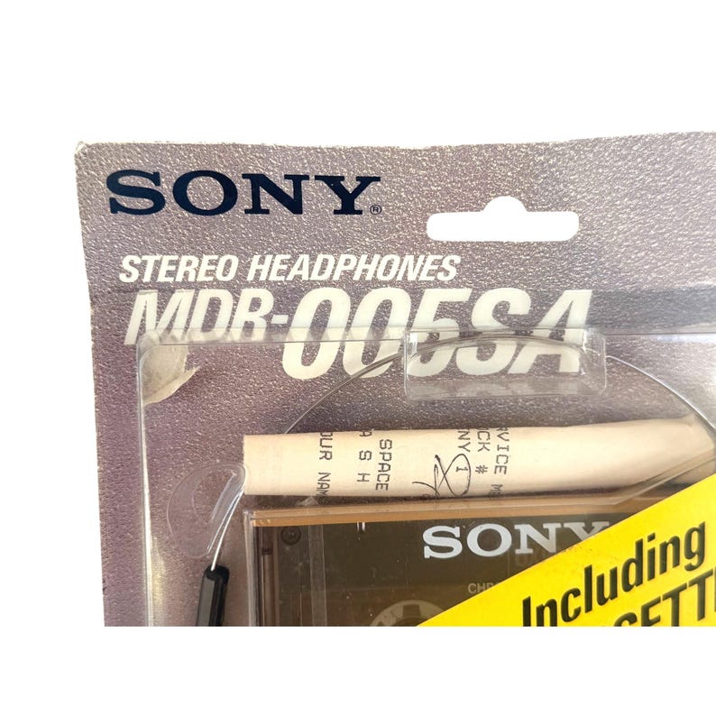May include: A Sony MDR-005SA stereo headphones package with a grey cardboard backing. The clear plastic blister pack contains the headphones and a white cylindrical component with text. A yellow sticker on the bottom right reads Including.
