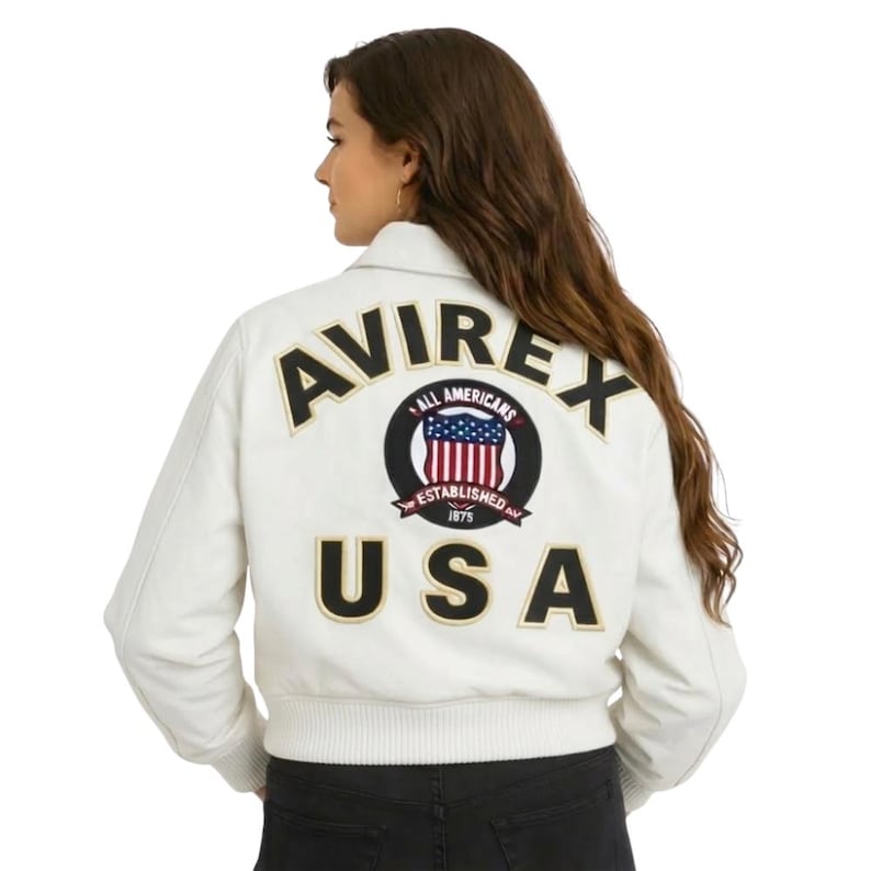 May include: A white ceramic mug with a black handle and the text "But First, Coffee" in a bold, black font. The mug is set against a blurred background, suggesting a cozy setting.