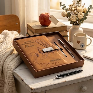 Puede incluir: Un diario de piel sintética color canela en una caja marrón, con una ilustración de Winnie the Pooh, el texto "Never forget the difference you make Ms. Sara" y "Thank you, Sam", un cierre metálico y un bolígrafo negro y plateado a juego.