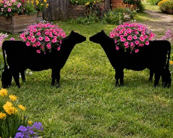 May include: Two black cow-shaped garden planters standing on a green lawn. Each silhouette features a large, rounded mound of vibrant pink petunia flowers growing from the back, creating a colorful floral display in a garden setting.