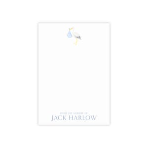 Può includere: Carta bianca con una cicogna che trasporta un fagotto blu. Il testo "FROM THE NURSERY OF" e il nome "JACK HARLOW" sono stampati in azzurro in basso. La cicogna ha zampe e becco gialli.