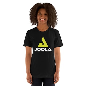 May include: Black t-shirt with a neon green and white JOOLA logo. The logo is a stylized triangle with the brand name below it in white capital letters. The shirt is made of a soft material and is being worn by a person.