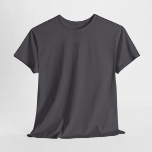 Puede incluir: Una camiseta gris oscuro de manga corta y cuello redondo. La tela parece suave y ligeramente arrugada, lo que sugiere un ajuste c&oacute;modo. La camiseta se presenta sobre un fondo neutro, destacando su dise&ntilde;o sencillo.