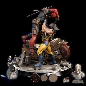 May include: A detailed collectible statue featuring a yellow and blue costumed figure lifting a red and black costumed figure. The base includes debris, a shield, a small bust labeled STAN LEE, and two small paint jars on a circular platform.