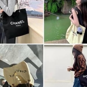Puede incluir: Un bolso tote de lona en color negro o crema con el texto CHANEL PARIS en letras blancas o negras. El bolso incluye una correa de hombro de cadena y una silueta rectangular, mostrado en varios entornos con diferentes atuendos.