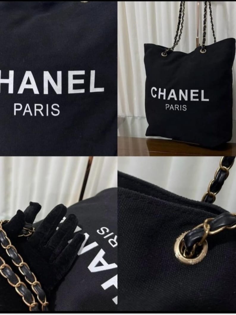 Puede incluir: Un bolso tote de lona negra con el texto blanco CHANEL PARIS impreso en la parte frontal. El bolso incluye ojales de metal dorado y una correa de cadena para el hombro entrelazada con tiras de cuero negro, ofreciendo un aspecto estructurado.