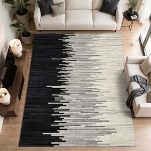 May include: A rectangular area rug featuring a gradient pattern of horizontal stripes that transition from solid black on the left side to shades of gray and white on the right side, creating a textured, linear design across the entire surface.