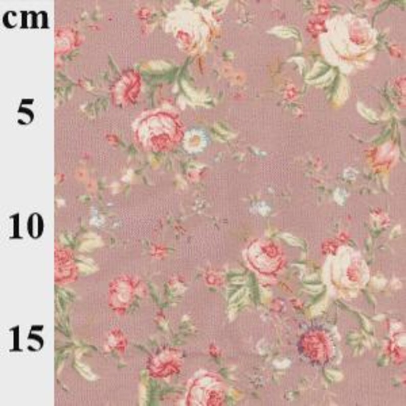 May include: Close-up of a floral fabric with a repeating pattern of pink and cream roses, green leaves, and small blue flowers on a mauve background. The fabric is measured in centimeters, with a visible scale up to 15 cm.