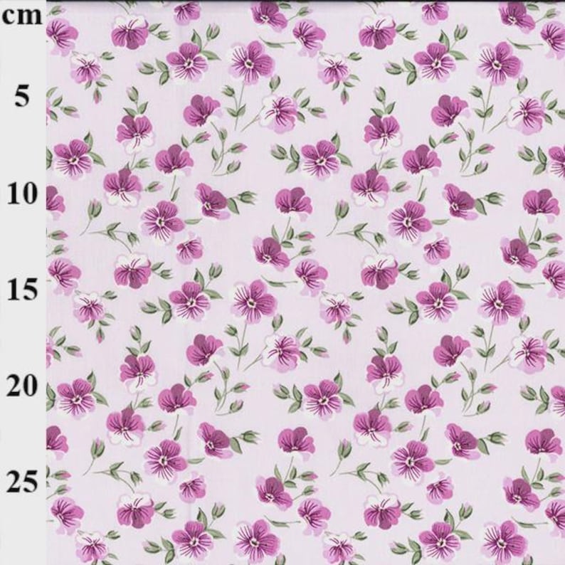 May include: Floral fabric with a repeating pattern of purple and white flowers and green stems on a light pink background. The fabric is marked with a centimeter ruler along the left edge.