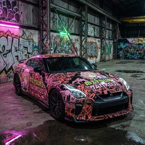 以下が含まれることがあります： ピンクと黒のスポーツカー。アニメをテーマにしたカスタムラップが施され、落書きで覆われた倉庫の中に駐車されています。車のデザインにはアニメのキャラクターと日本語のテキストが含まれています。黒いリムがあり、濡れたコンクリートの床に駐車されています。