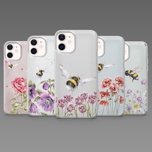 May include: A collection of five phone cases with floral and bee designs. Each case features a different watercolor illustration of flowers and bees. The cases are clear with a glossy finish, showcasing the artwork. The designs include roses, poppies, and daisies.