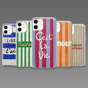 Op de afbeelding: Een verzameling van vijf telefoonhoesjes met kleurrijke verticale streepontwerpen. Elk hoesje heeft een ander kleurenschema, waaronder blauwe, groene, rode, roze en witte strepen. Sommige hoesjes hebben tekst, zoals "C'est la Vie."