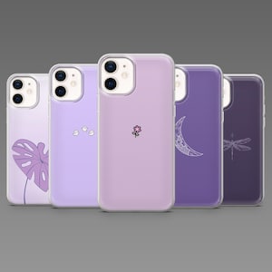 Puede incluir: Cinco fundas de teléfono en fila, cada una con un diseño diferente. Las fundas son de varios tonos de morado. Los diseños incluyen una hoja, fantasmas, una flor, una luna creciente y una libélula.