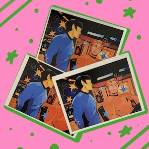 May include: Three identical rectangular art prints featuring a stylized illustration of two figures in a spaceship control room. One figure wears a blue uniform and the other wears an orange uniform. The prints are arranged on a bright pink background.