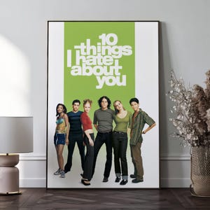 May include: A framed poster with the film title "10 Things I Hate About You" in white text on a green panel. The poster shows six young people in casual attire. The poster is displayed against a white wall.