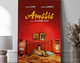May include: A framed movie poster for the film "Amélie" with a red background. The poster features the film's title in yellow script, the names of the actors, and a scene from the movie. The poster is displayed in a room with a bed and artwork.