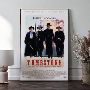 Könnte beinhalten: Ein gerahmtes Filmplakat für den Film "Tombstone". Das Poster zeigt vier Männer in schwarzen Anzügen und Hüten, mit dem Text "Justice Is Coming" über dem Titel. Der Titel "TOMBSTONE" steht in großen roten Buchstaben.