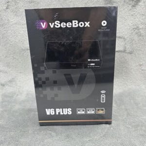 May include: A black V6 PLUS smart media player box with the vSeeBox logo in purple and white. The box has the words "SMART MEDIA PLAYER" and "4K Ultra High Definition" printed on it. The box also has a remote control icon.