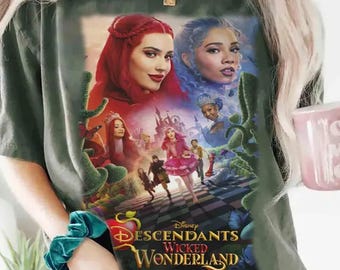 May include: A moss green short-sleeve t-shirt featuring a graphic print of the Disney Descendants Wicked Wonderland movie poster. The design includes multiple characters, a castle, and the text Disney Descendants Wicked Wonderland in gold.