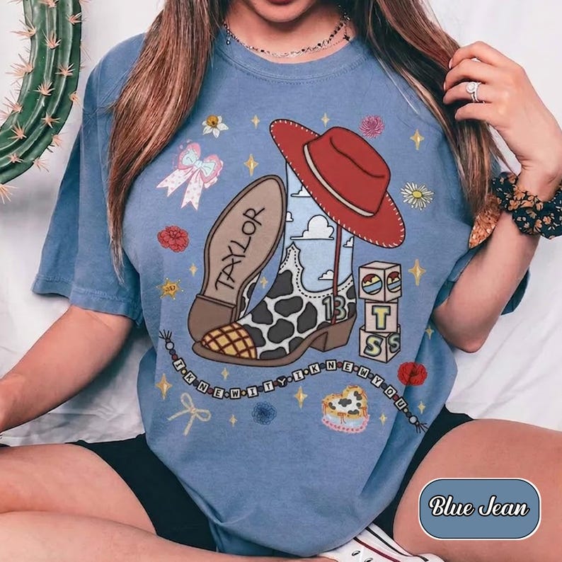Pu&ograve; includere: Una t-shirt blu con una stampa grafica di uno stivale da cowboy con motivo a macchie di mucca con il nome Taylor, un cappello da cowboy rosso, blocchi impilati con le lettere T, S e il numero 13, e una collana di perline con il testo I KNEW IT I KNEW YOU.