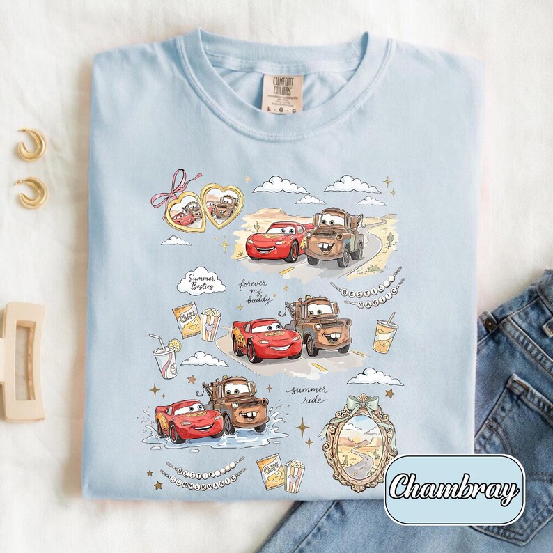 Puede incluir: Camiseta azul claro con ilustraciones de dibujos animados de los personajes de Cars, Rayo McQueen y Mate, con los textos "Summer Besties" y "Summer Ride". Cuello redondo y mangas cortas.