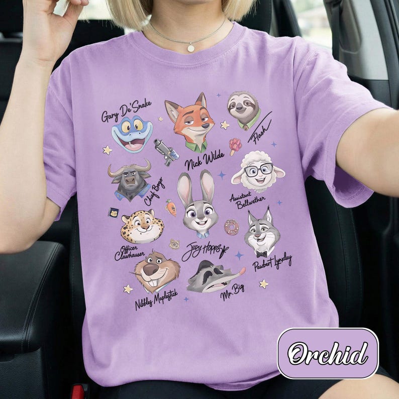 May include: A lilac t-shirt with cartoon portraits of Zootopia characters, such as Nick Wilde and Judy Hopps. Each character has their name above their portrait. The word "Orchid" is printed on the bottom right of the shirt.