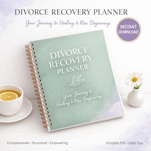Op de afbeelding: Een spiraalgebonden "Divorce Recovery Planner" met een zachtgroene kaft. De titel is in het wit, met de tekst "Your Journey to Healing & New Beginnings" eronder. Een kopje thee met citroen en een vaasje met een madeliefje.