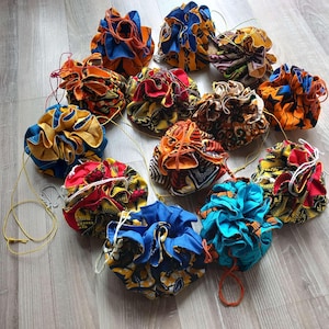 Peut inclure: Plusieurs pochettes à cordon colorées et à motifs. Les pochettes sont faites de tissu de différentes couleurs, notamment bleu, orange, rouge et jaune. Chaque pochette a une fermeture à cordon et une forme ronde.