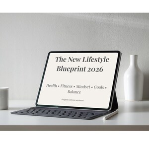 Op de afbeelding: Een digitale wellness-werkboek getiteld "The New Lifestyle Blueprint 2026" weergegeven op een tablet met een toetsenbord. De tekst bevat "Gezondheid, Fitness, Mindset, Doelen, Balans". Een witte mok, vaas en pen zijn ook zichtbaar.