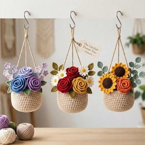 Puede incluir: Tres cestas de flores de ganchillo colgadas de ganchos metálicos. Cada cesta contiene una disposición diferente de flores coloridas, incluyendo rosas, girasoles y margaritas. Las cestas están suspendidas por hilo.