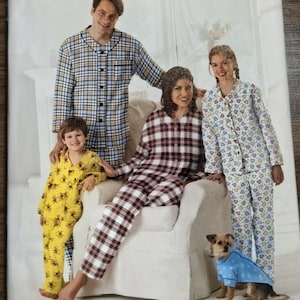 May include: A Simplicity sewing pattern envelope 2771 for pajamas in sizes XS-L and XS-XL. The cover features illustrations of four people wearing various pajama sets with plaid, heart, and monkey prints, plus a dog wearing a blue coat.