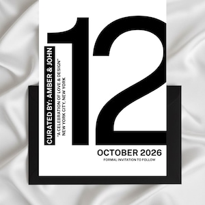 May include: A black and white invitation card with the number 12 in large, bold font. The card includes the text "October 2026" and "Formal invitation to follow". The card is in a black envelope.