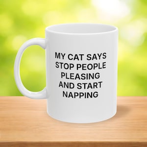 Taza divertida con el mensaje "Mi gato dice: 'Deja de complacer a la gente y empieza a dormir la siesta'". Taza de café para amantes de los gatos con una linda cara de gato en la parte posterior.