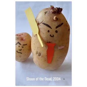 May include: Two potatoes decorated with faces, one holding a yellow paper sword and wearing a red paper tie. The larger potato has a sticker that says "Shaun". The text "Shaun of the Dead, 2004" is at the bottom.