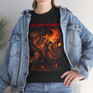 May include: Black t-shirt featuring a fiery dragon illustration with the text "Fear the Flame" in red. The dragon is depicted in shades of orange and brown, with flames engulfing its body. The shirt is made of a soft material.