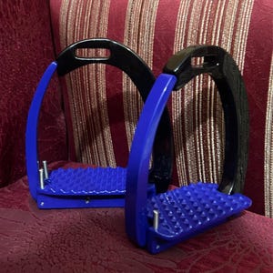 Puede incluir: Dos estribos de caballo azules y negros. Los estribos tienen una base azul con superficie texturizada y un arco negro. Estos estribos están diseñados para uso ecuestre.