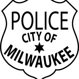 May include: A black and white police badge with the words "POLICE CITY OF MILWAUKEE" in bold, sans-serif font. A black star is centered below "CITY OF". The badge has a shield shape with a decorative border.