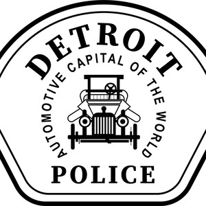 May include: Black and white Detroit Police badge with a vintage car illustration. The badge is shaped like a shield and features the text "DETROIT" at the top, "AUTOMOTIVE CAPITAL OF THE WORLD" around the car, and "POLICE" at the bottom.