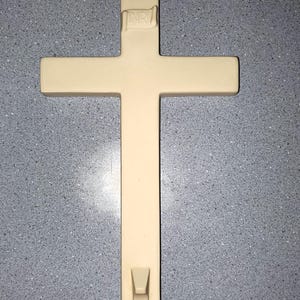 May include: A white ceramic cross with the inscription "INRI" on the top. The cross has a hook on the bottom.