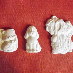 May include: Three white ceramic figurines of animals. A squirrel, a dog, and a bear. The figurines are all in a standing position and have a simple, cartoonish style.