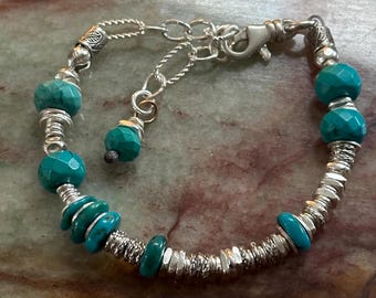 May include: A turquoise and silver bracelet with a chain extender. The bracelet features turquoise beads and silver spacers.