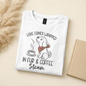 May include: White t-shirt featuring a cartoon dog with a red bandana, a coffee cup, and the text "LOVE COMES WRAPPED IN FUR & COFFEE Steam". The shirt is folded and has a Gildan tag.