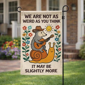 Może przedstawiać: Beżowa flaga ogrodowa z napisem "WE ARE NOT AS WEIRD AS YOU THINK" i "IT MAY BE SLIGHTLY MORE". Flaga przedstawia kreskówkowego jeża grającego na gitarze podczas jazdy na ślimaku, z uśmiechniętym słońcem i kwiatowymi akcentami.