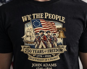 Könnte beinhalten: Schwarzes T-Shirt mit patriotischem Design. Die Grafik enthält den Text "WE THE PEOPLE", eine amerikanische Flagge, Soldaten, ein Schiff und die Liberty Bell. Es enthält auch den Text "250 YEARS OF FREEDOM" und "JOHN ADAMS 1745-1816".