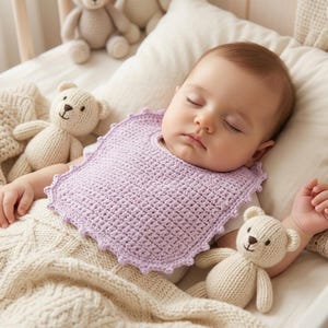 May include: A sleeping baby wearing a lavender crochet bib, nestled in a crib with a cream-colored blanket and teddy bears. The bib has a scalloped edge. The scene evokes a sense of comfort and tranquility.
