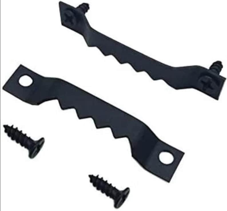 May include: Two black sawtooth picture hangers with screws. The hangers have a series of angled teeth along one edge and a hole for mounting. The screws are black and have a Phillips head.