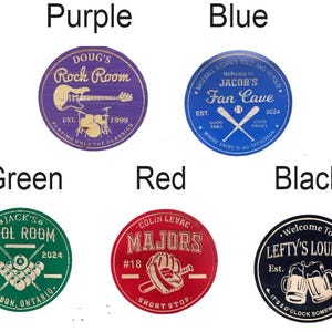 May include: Circular wooden signs in purple, blue, green, red, and black. Each sign features a different design, including a guitar, baseball bats, pool balls, a baseball glove, and beer mugs, with text such as "Rock Room" and "Fan Cave".